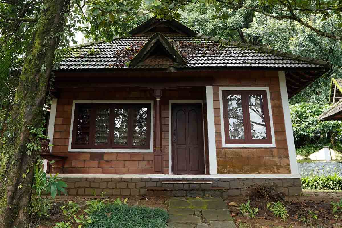 Traditional cottage at Misty Woods resort surrounded by greenery in Coorg