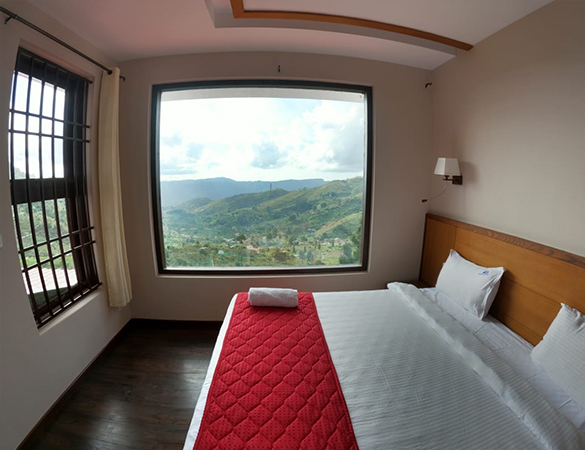 Premium Valley View Room at Warmth Hill Crest – elegant interiors with comfortable bedding, modern amenities, and large windows overlooking the scenic hills of Kodaikanal, perfect for a family resort in Kodaikanal.