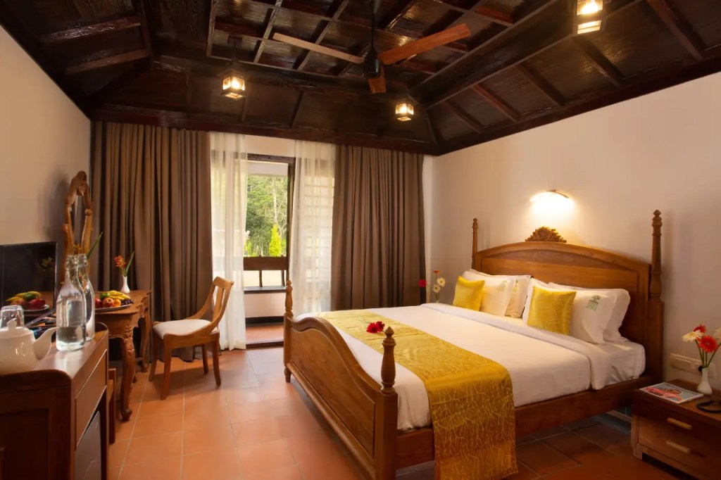 Luxurious bedroom at Heaven Inn Munnar featuring elegant wooden interiors, comfortable bedding, and scenic mountain views.