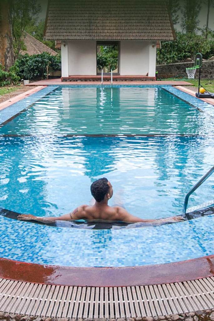 Open-air swimming pool at Misty Woods Resort Coorg surrounded by lush greenery and scenic hills