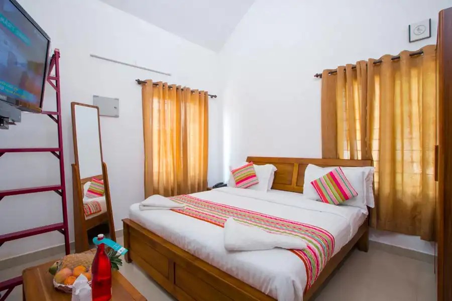 Comfortable bedroom at Misty Lake Resort Munnar with cozy bedding, modern interiors, and a private balcony overlooking scenic hills.