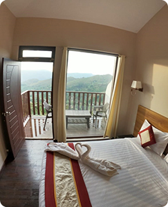 Comfortable, clean, and spacious room at Warmth Hill Crest, Kodaikanal, featuring modern interiors and a private balcony with breathtaking valley and hill views.